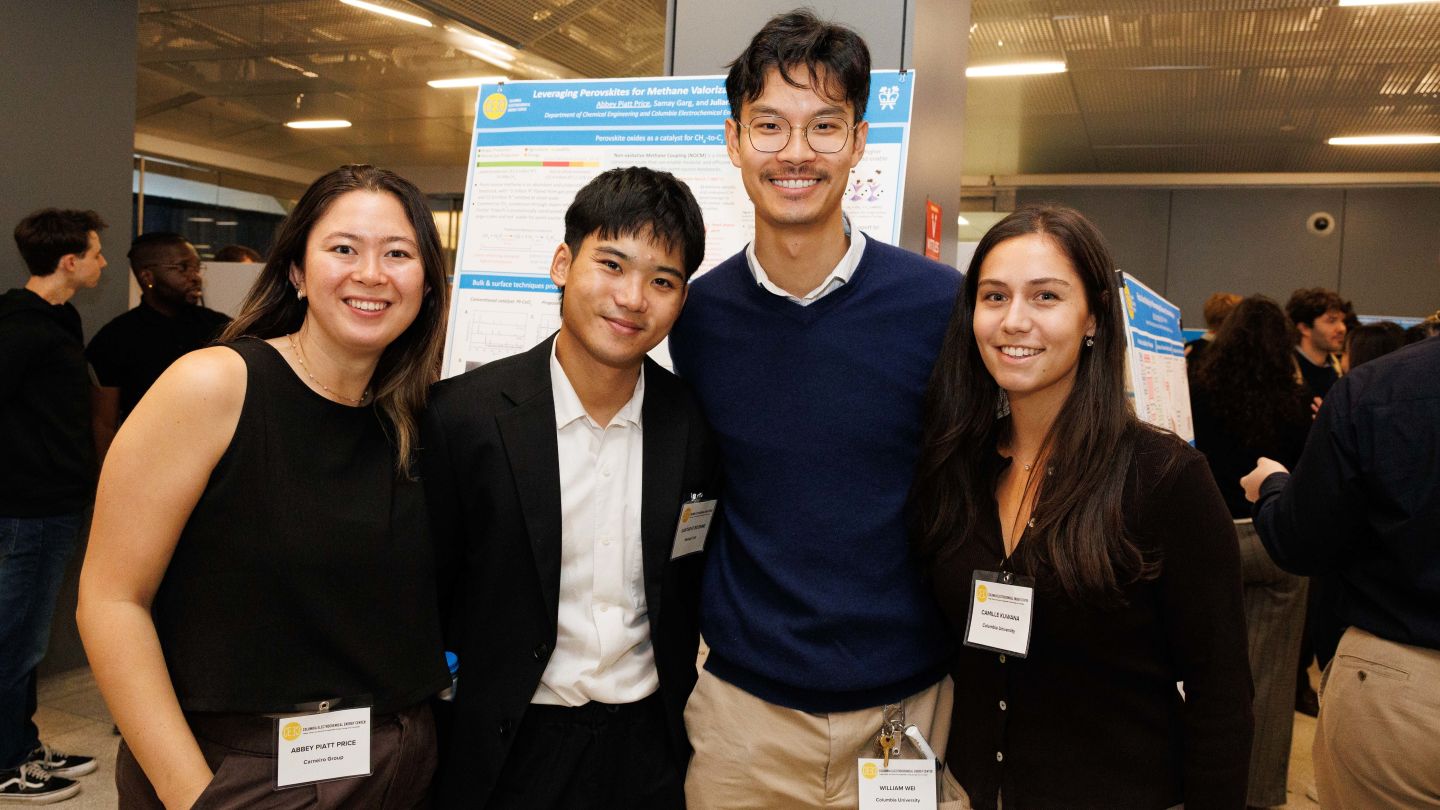 Four attendees pose together in front of research posters during a poster session at Columbia Engineering.