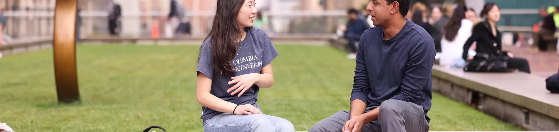 two people sitting on a ledge outside in a courtyard